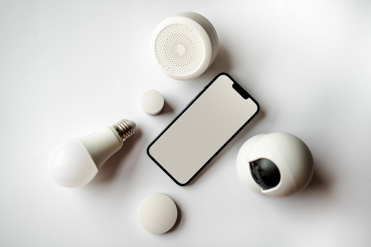 services-03 Flat lay of smartphone and smart home devices on a white backdrop, showcasing modern technology.