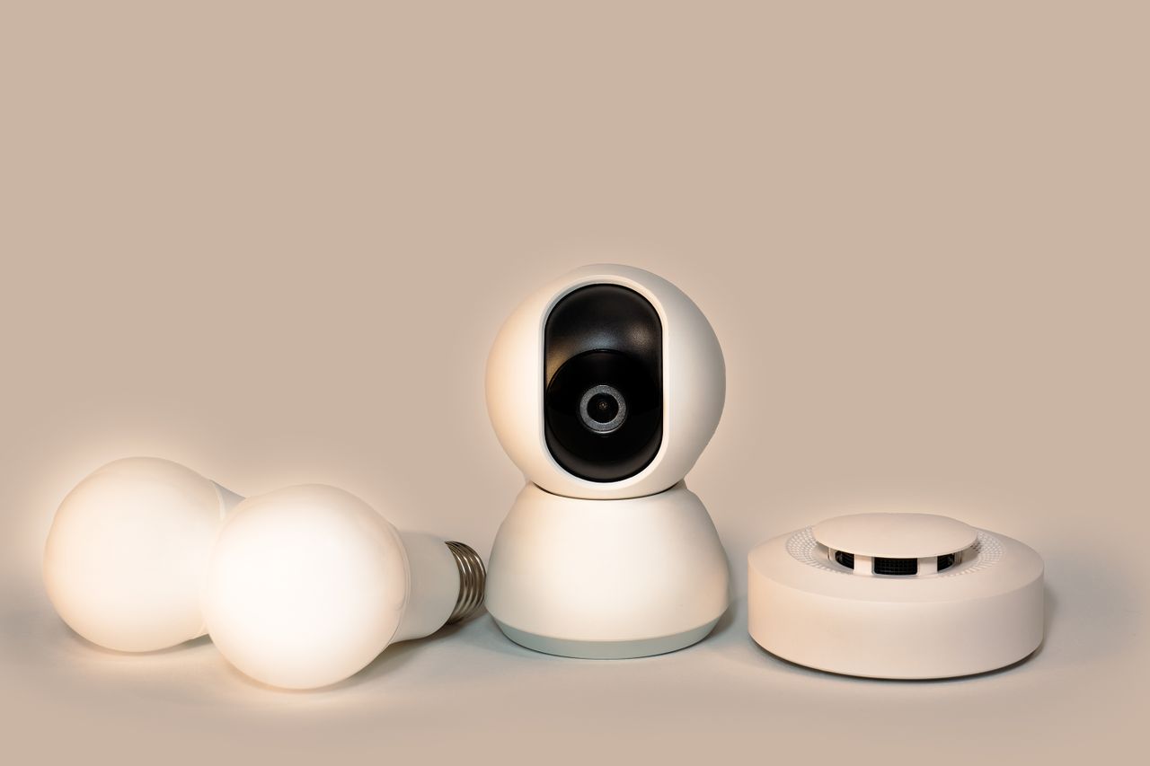 our-story A collection of modern smart home gadgets including a CCTV camera, LED bulbs, and a smoke detector.