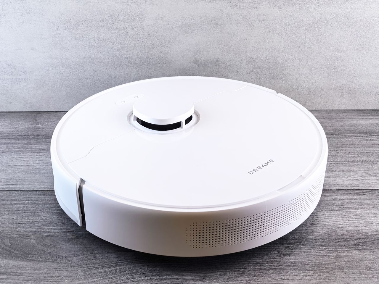 services-01 Sleek white robot vacuum cleaner on a wooden floor, perfect for smart home setups.